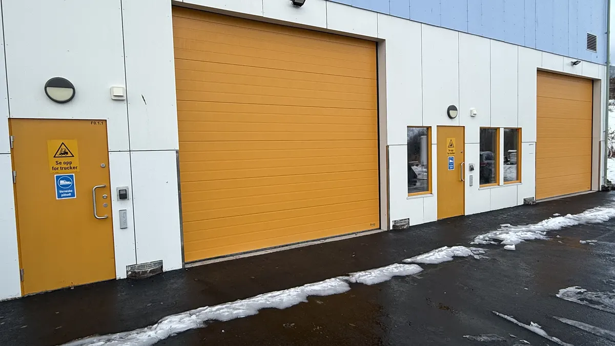 Gule industriporter og dører i en hvit fasade om vinteren